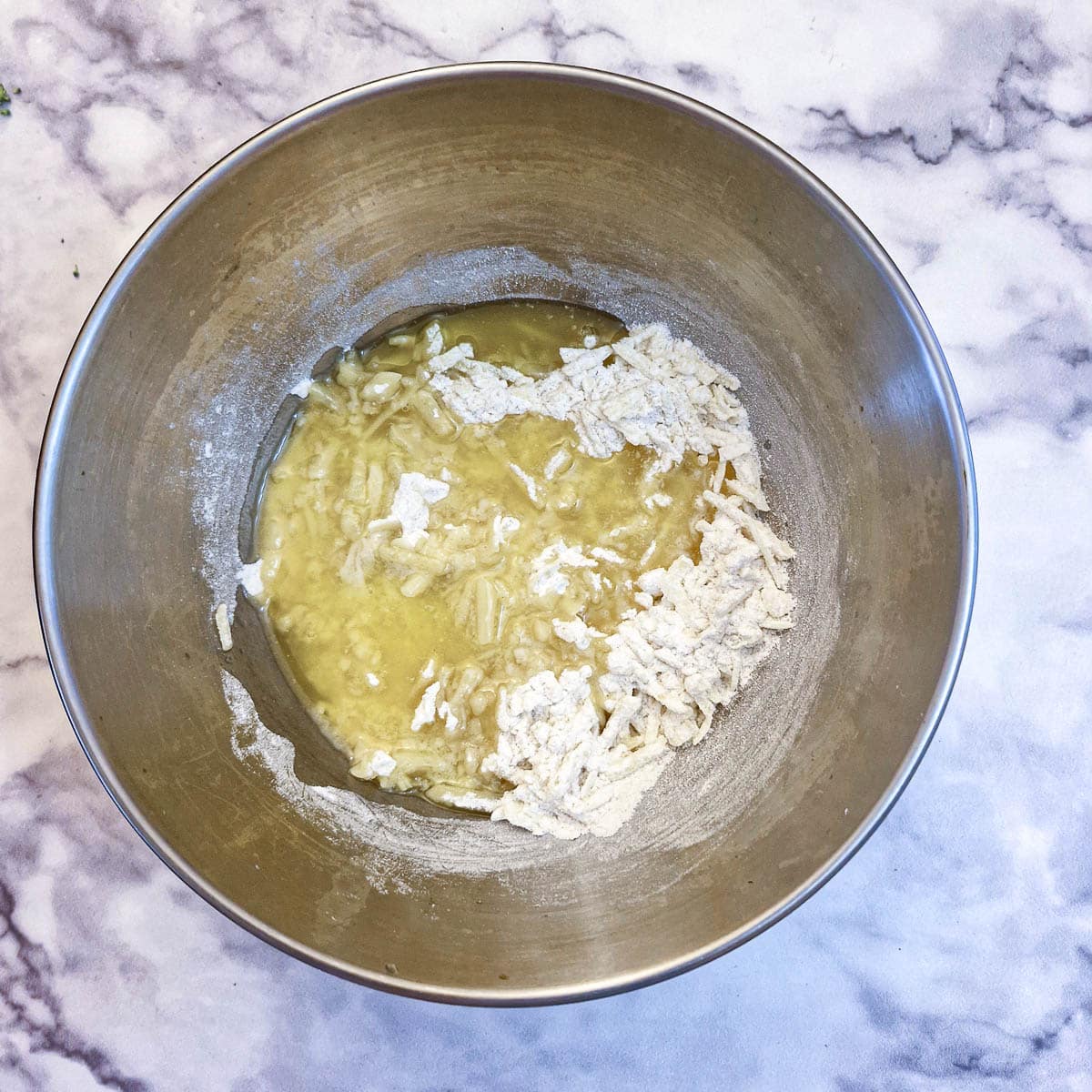 Melted butter poured into cheese and flour in a mixing bowl.
