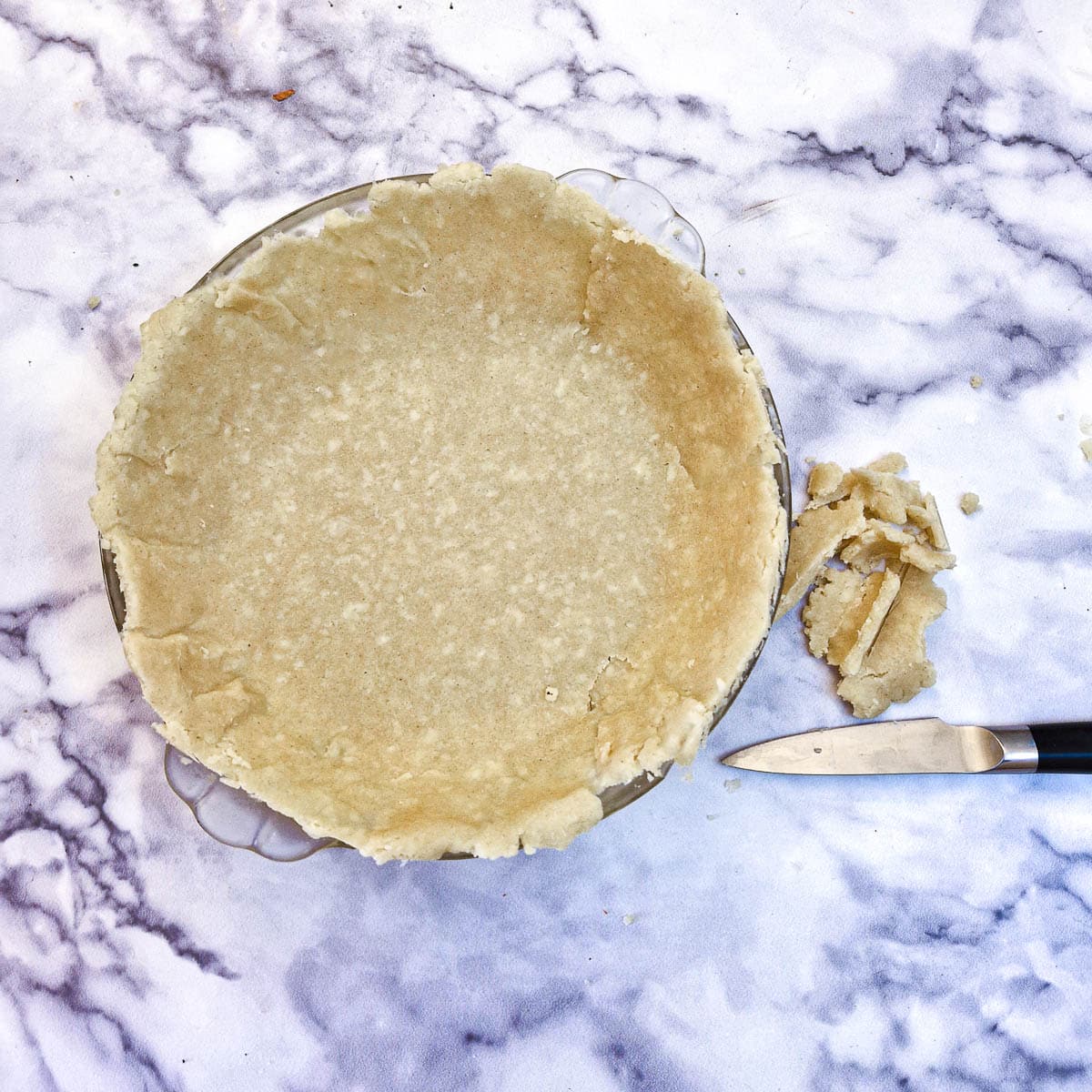 Cheese pastry in a baking dish with the edges being neatened with a sharp knife.