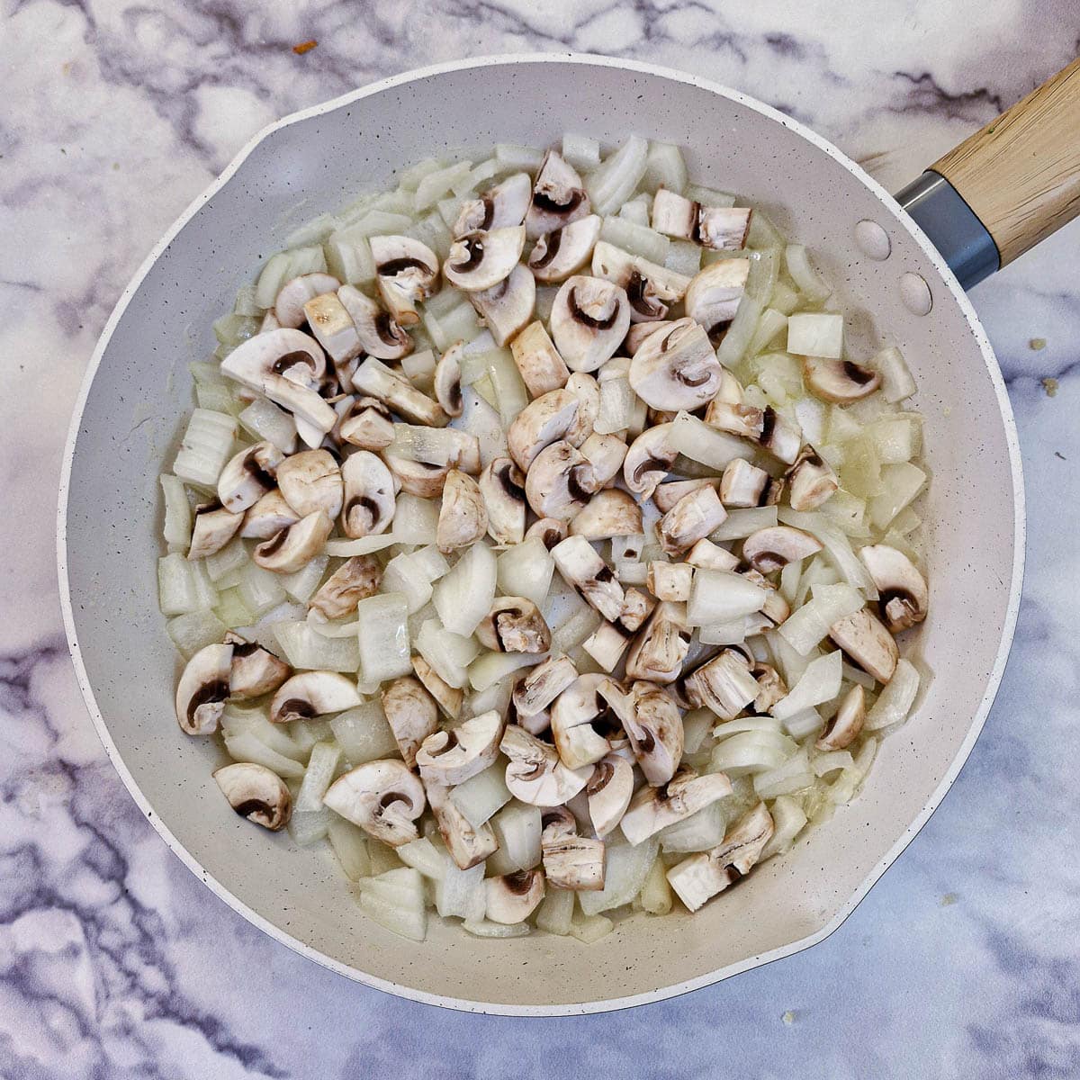 Chopped onions and mushrooms in a frying pan.
