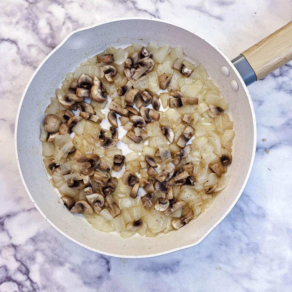 Softened chopped onions and mushrooms in a frying pan.