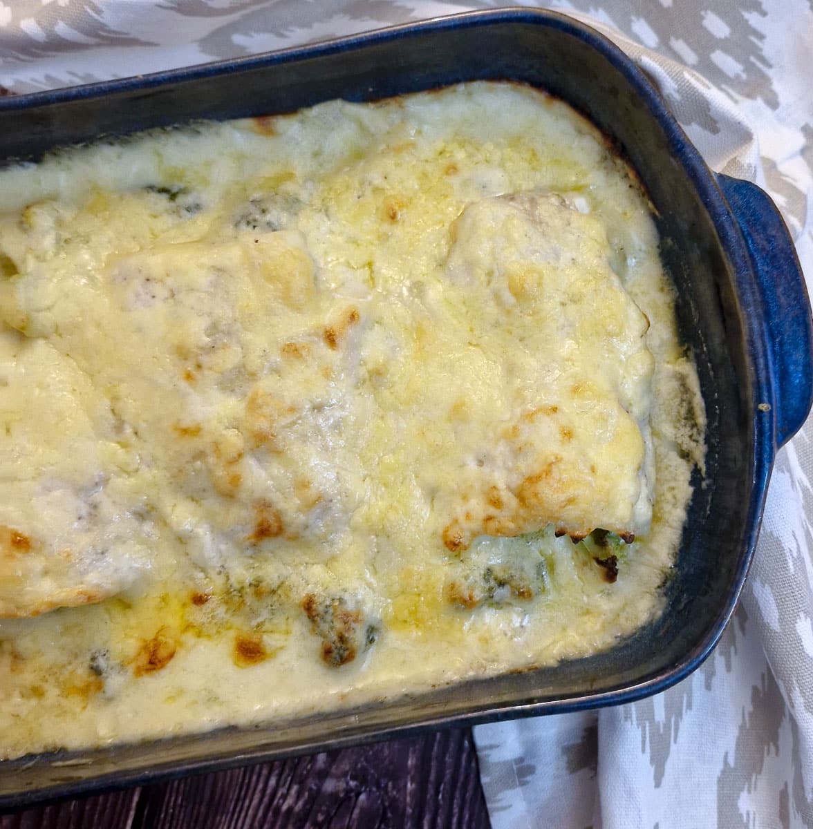 Overhead shot of a dish of cod and broccoldi bake covered in a cheesy sauce.