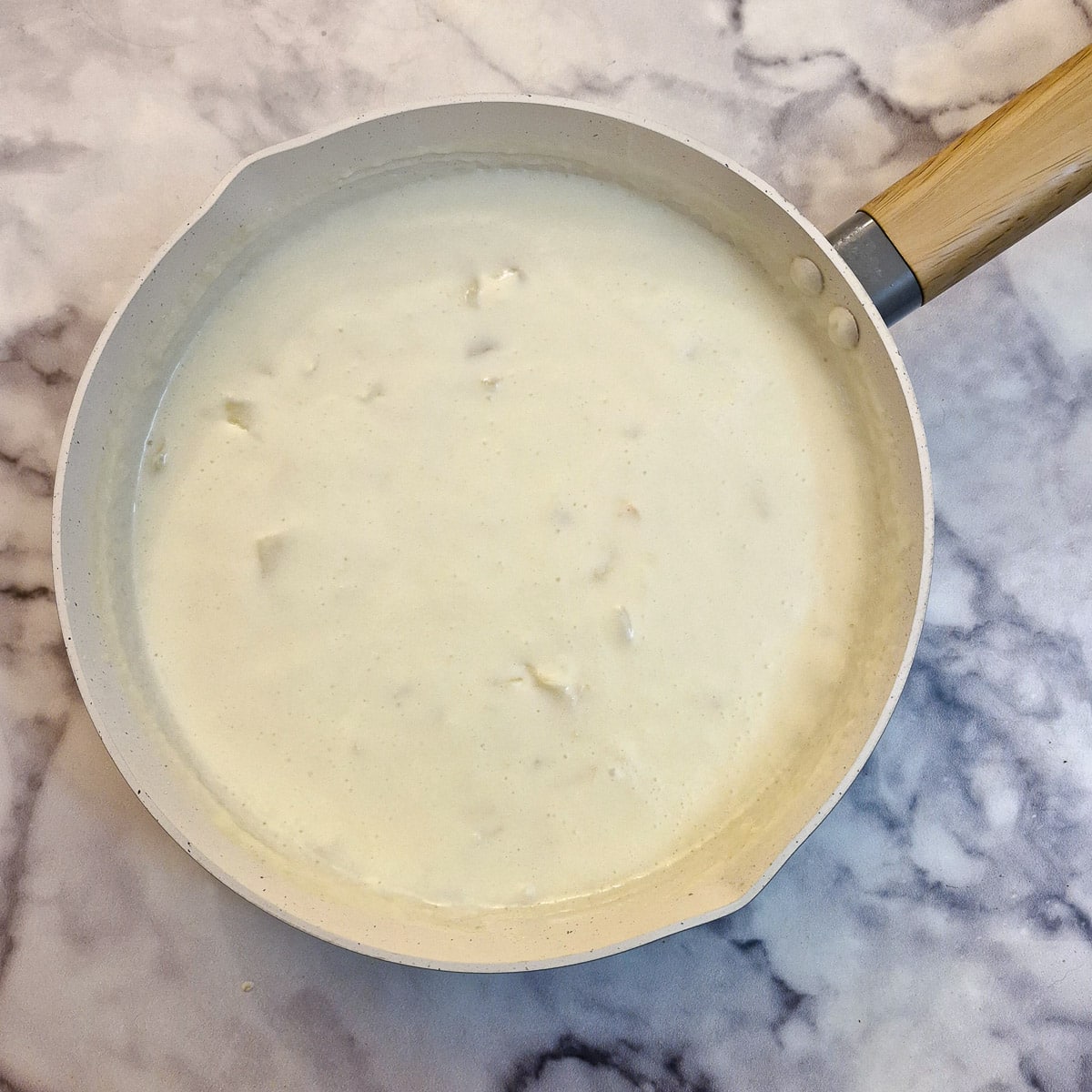 Milk added to the onions in a frying pan.