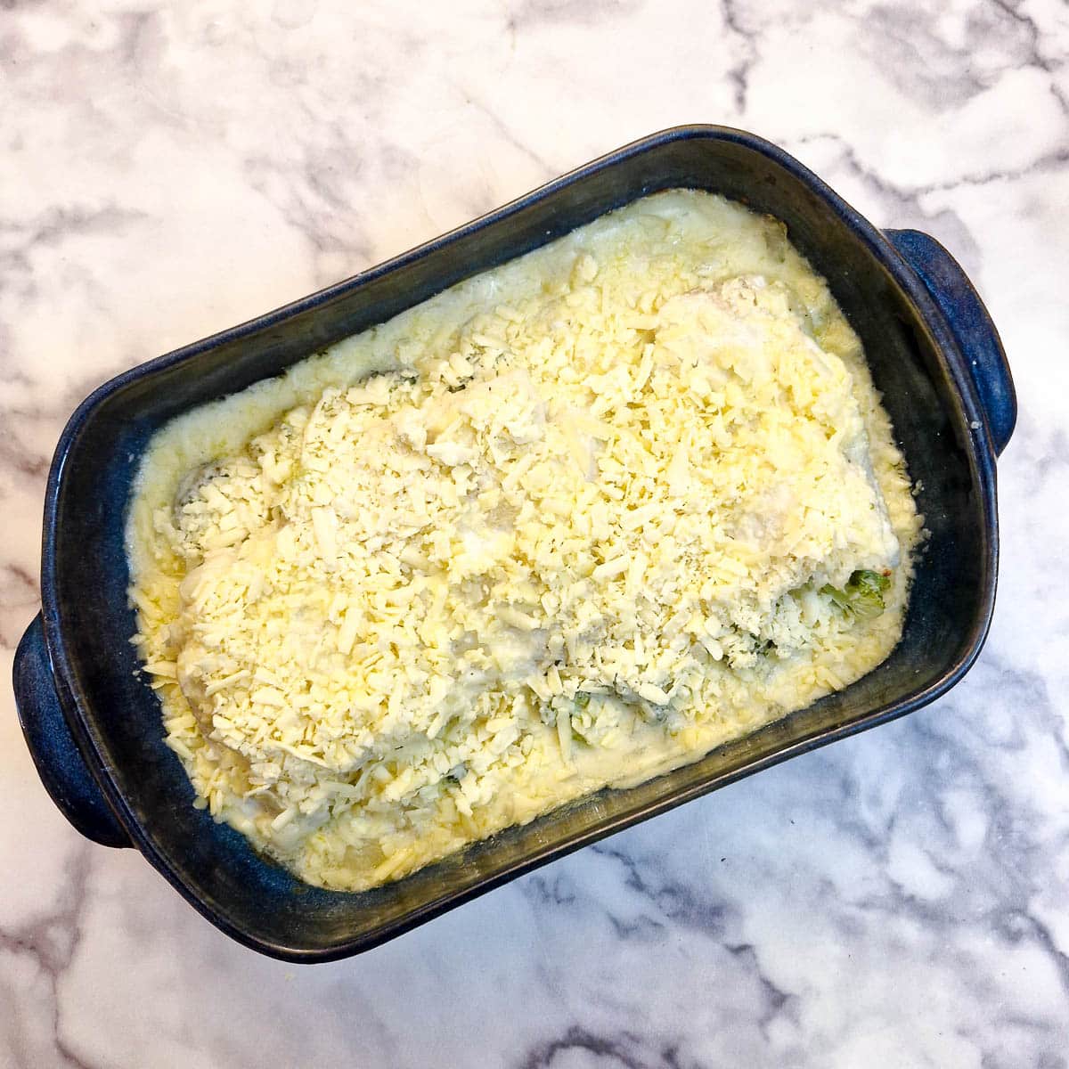 Grated cheese sprinkled on the cod and broccoli before it goes into the oven.