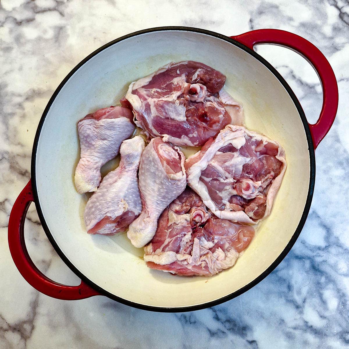 Chicken pieces browning in a casserole dish.