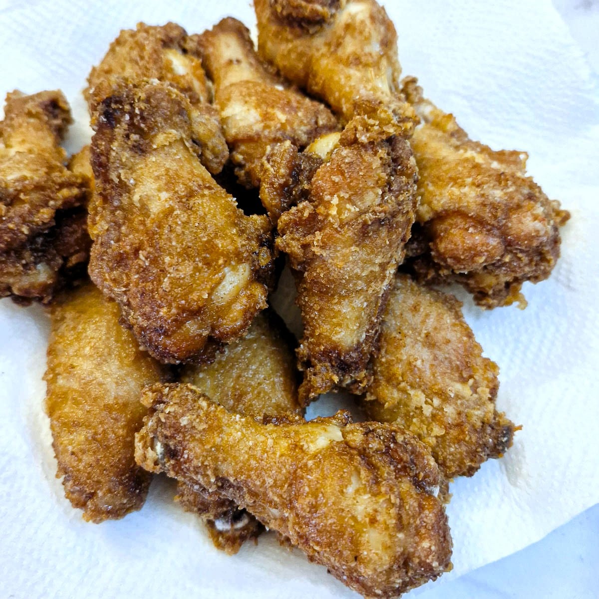 A pile of crispy chicken wings on a paper towel.