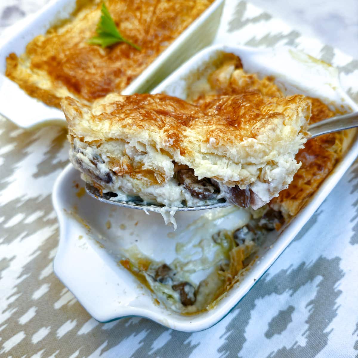 A slice of chicken pie being lifted from the dish on a serving spoon.