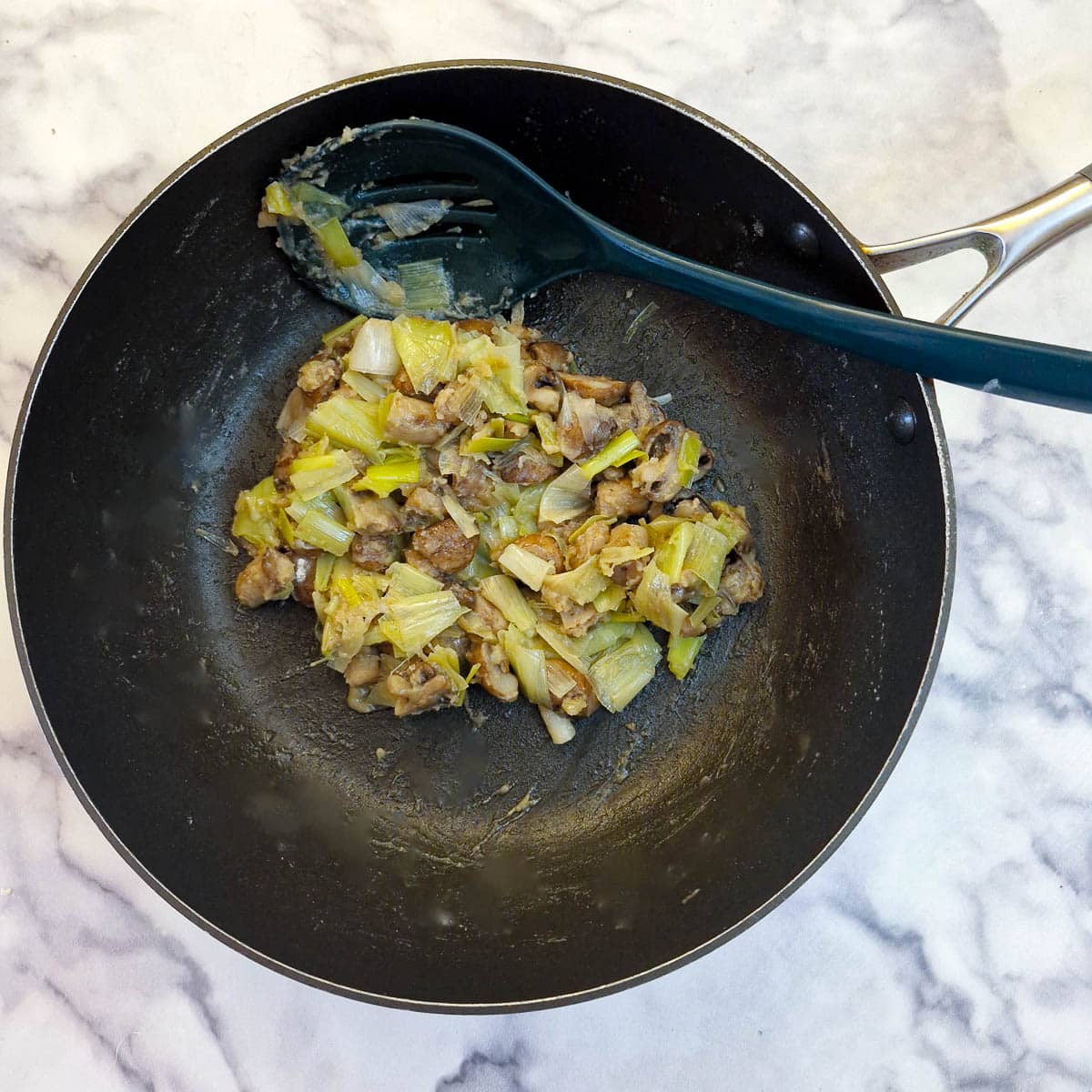 Flour mixed with leeks and mushrooms in a frying pan.