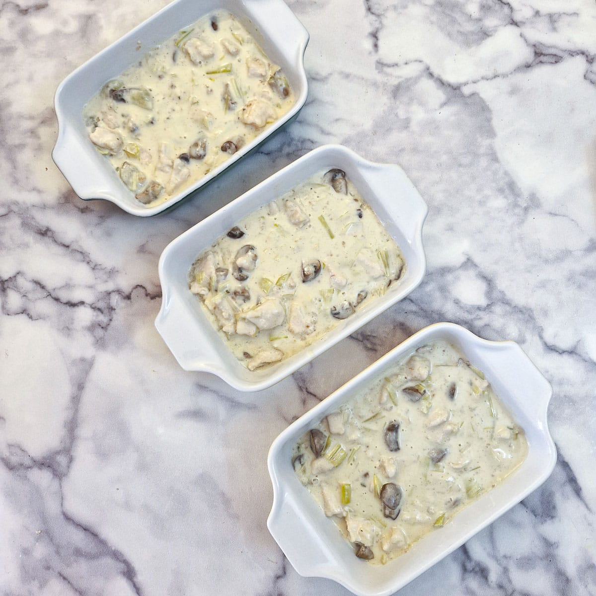 Three small dishes filled with chicken pie filling.