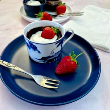 A microwave chocolate pot garnished with a strawberry in a blue and white cup on a blue plate.