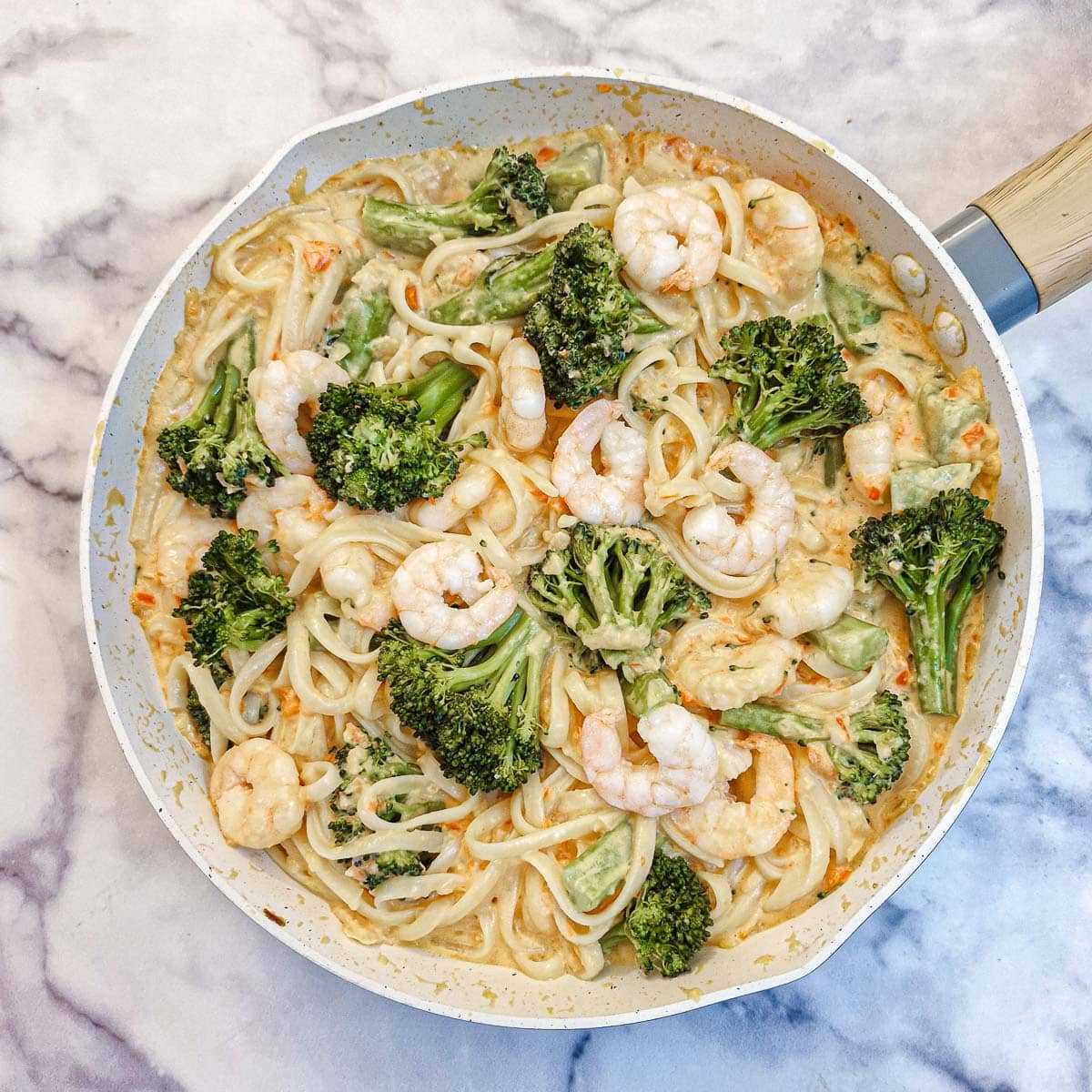 The finished dish of prawn and broccoli pasta in a frying pan.