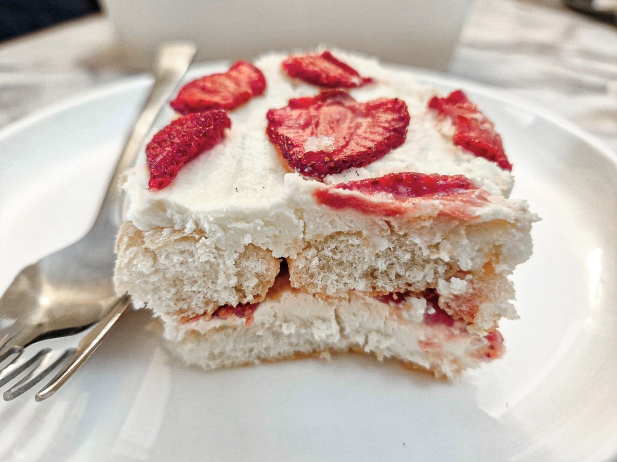 A slice of strawberry tiramisu on a white plate with a cake fork.