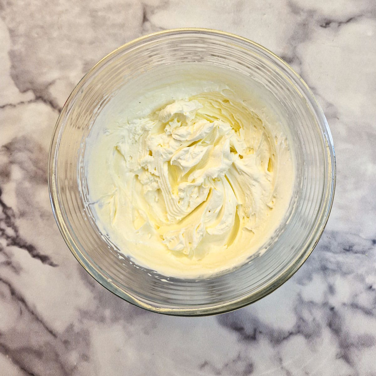 Double cream whippd to stiff peaks in a glass bowl.