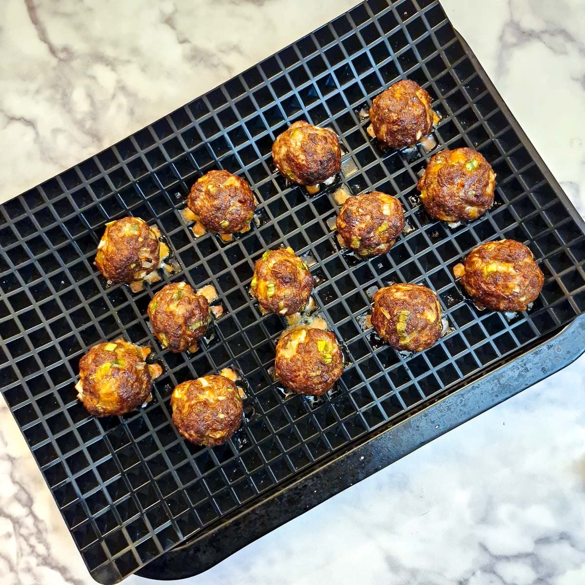 13 baked meatballs on a baking tray.