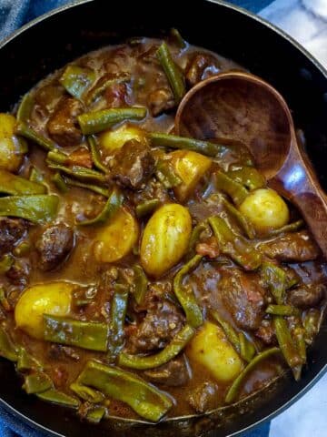 A black frying pan filled with green bean bredie.