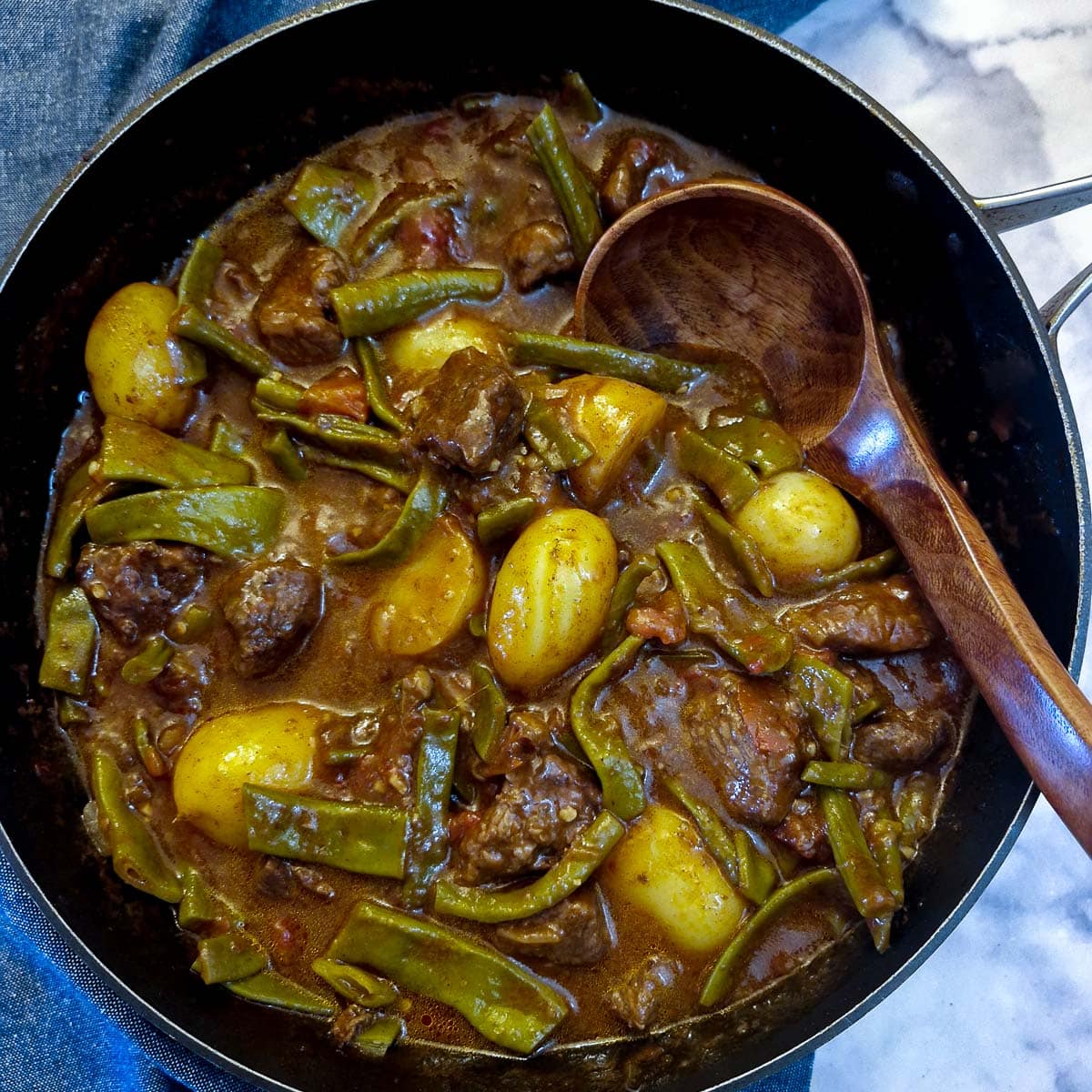A black frying pan filled with green bean bredie.