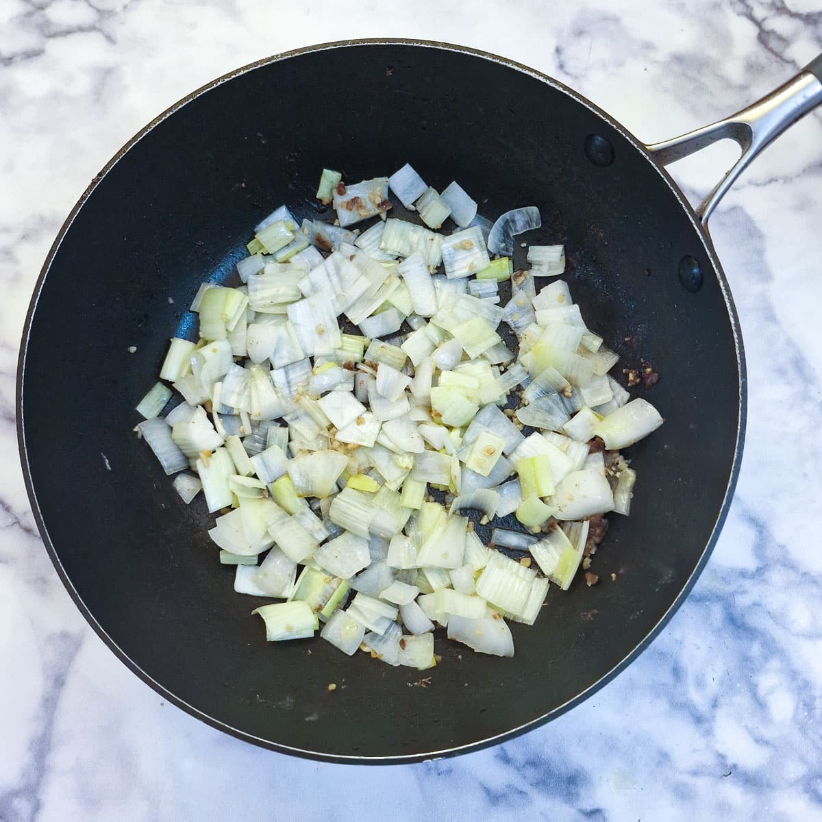 Onions softening in a frying pan.