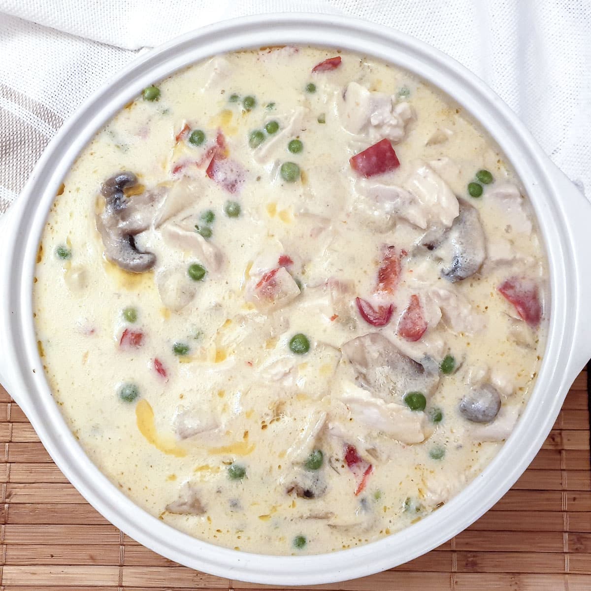 Chicken a la king in a white serving dish.