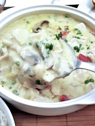 A dish of chicken a la king with a large serving spoon.