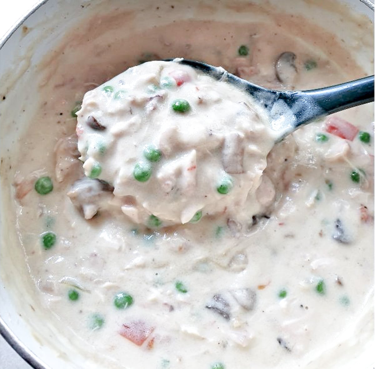 A spoonful of chicken a la king being lifted from the pan.