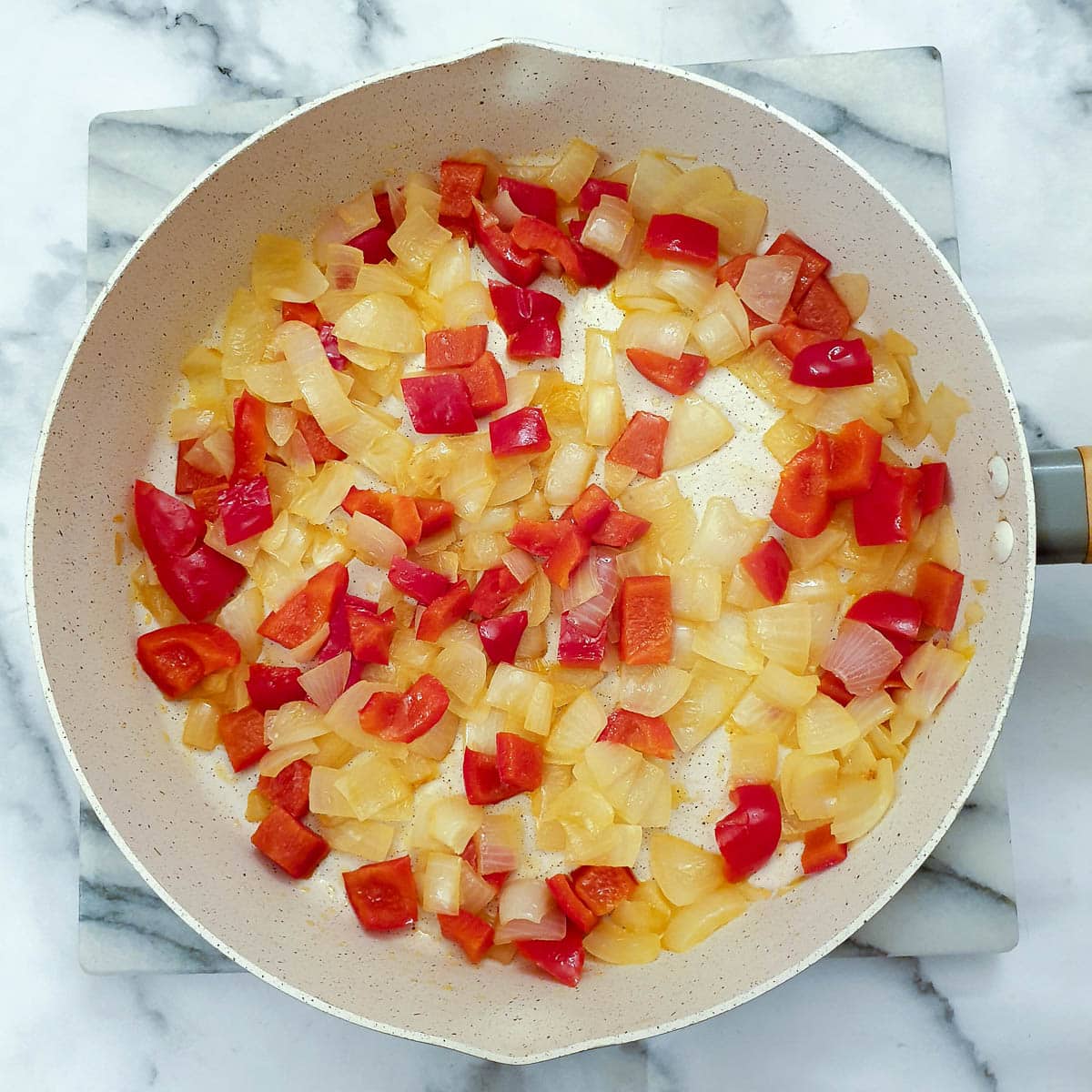 Red peppers and onions in a frying pan.