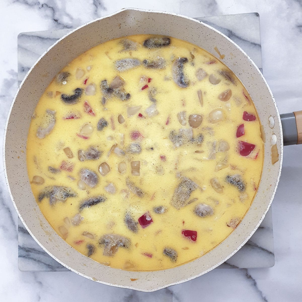 Milk added to the vegetables in a frying pan.
