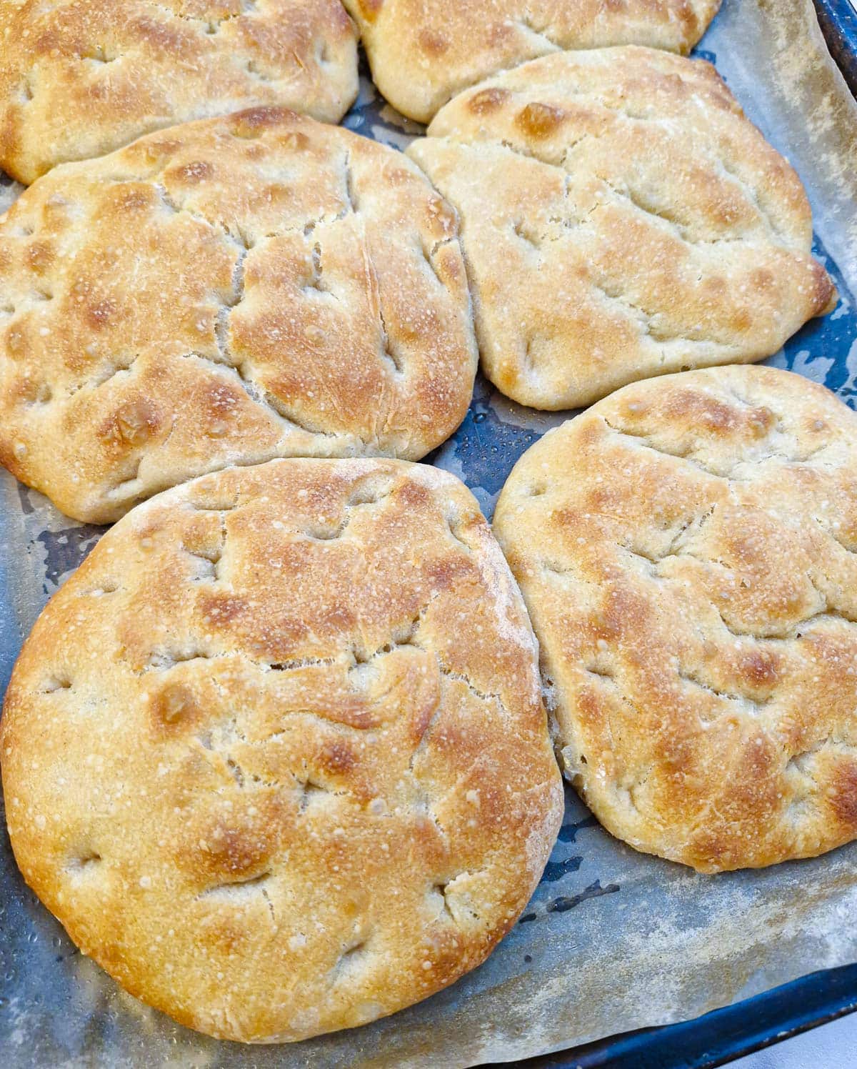 6 focaccia bread rolls on a baking tray.