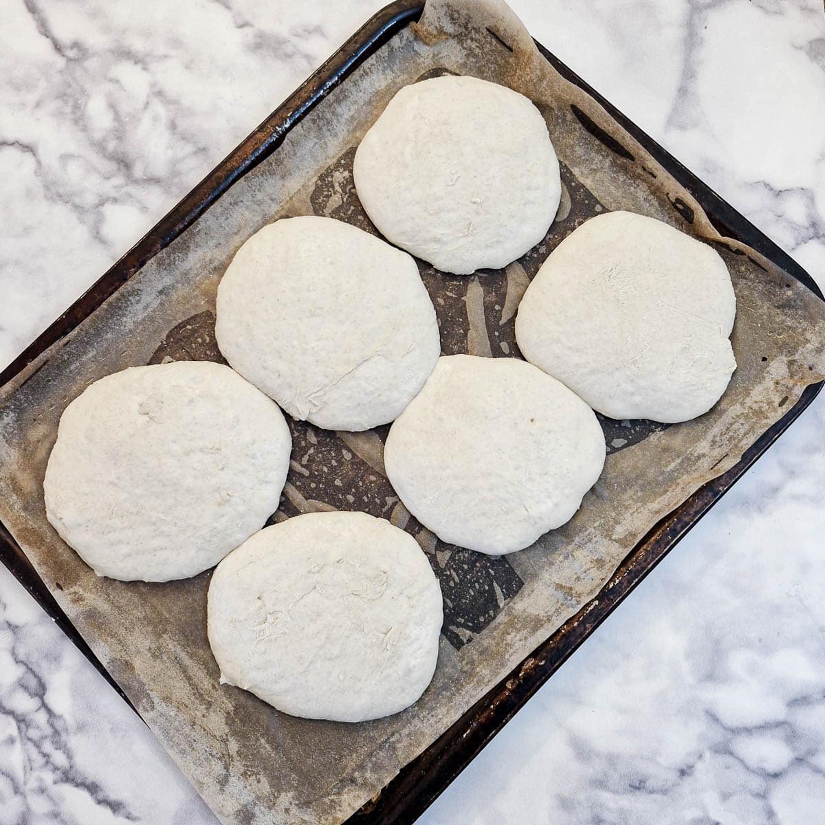 6 bread rolls on a baking sheet after having rested for 45 minutes.