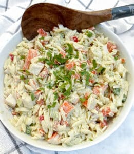 A dish of imitation crab salat with a large wooden serving spoon.