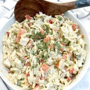 A dish of imitation crab salat with a large wooden serving spoon.