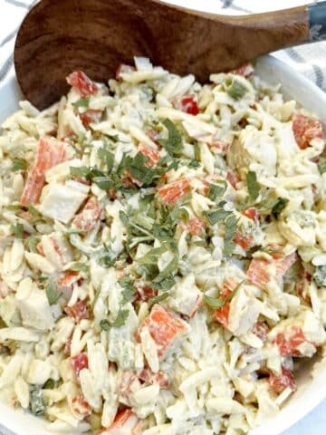 A dish of imitation crab salat with a large wooden serving spoon.