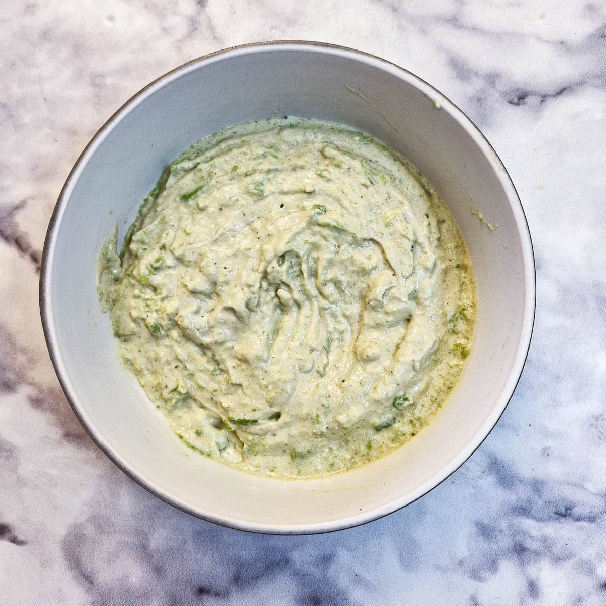 Avocado mixed with mayonnaise in a small white bowl.