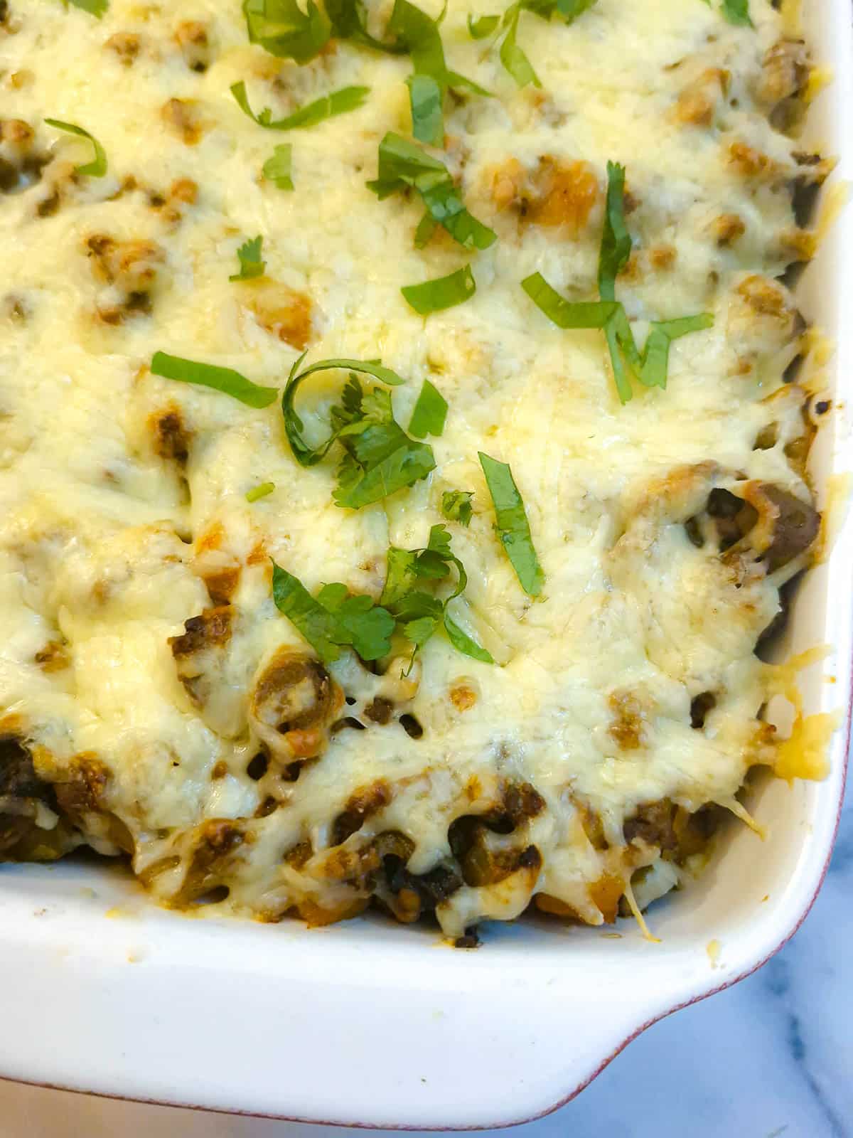 Close up of a mince and potato casserole topped with melted cheese.