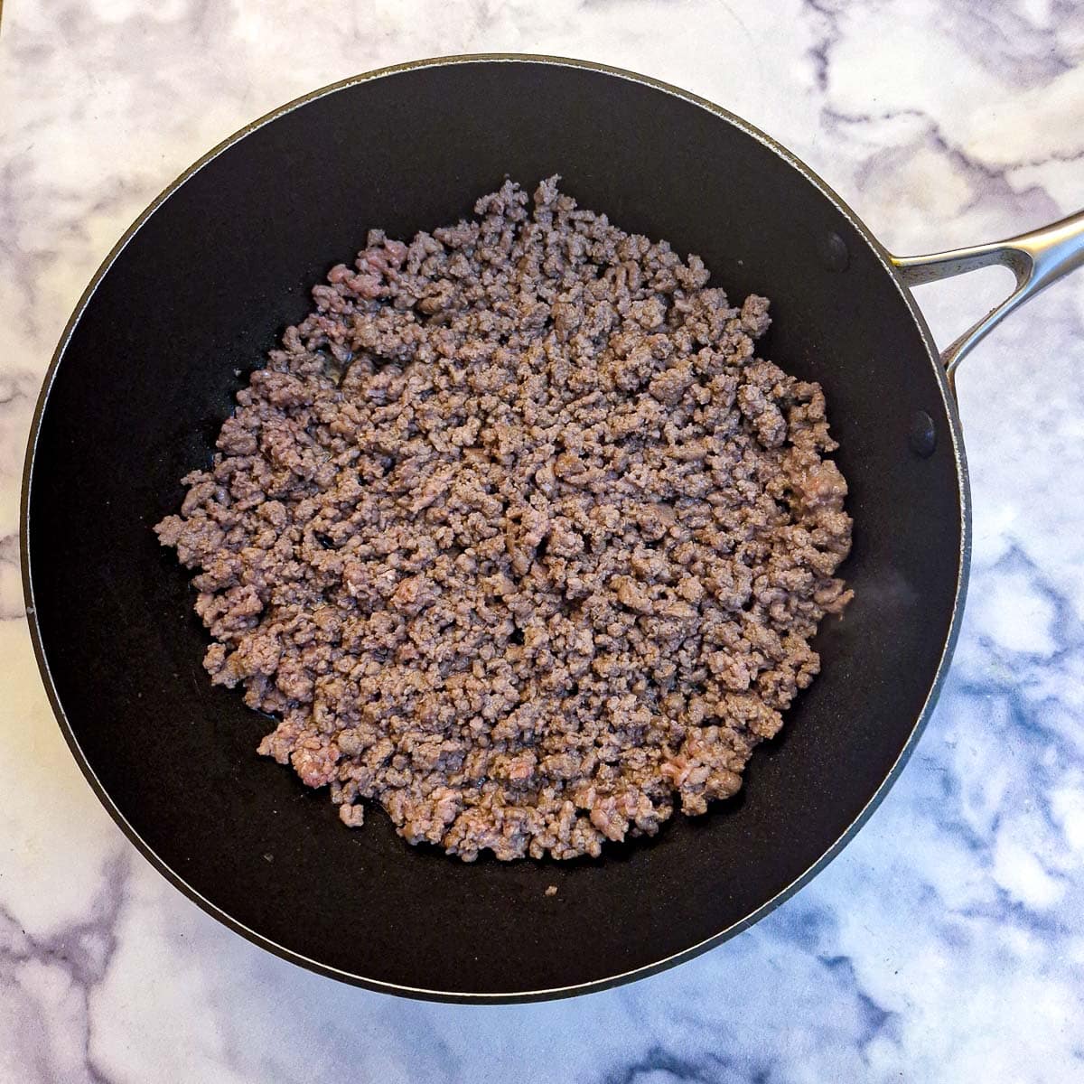 Browned beef mince in a black frying pan.
