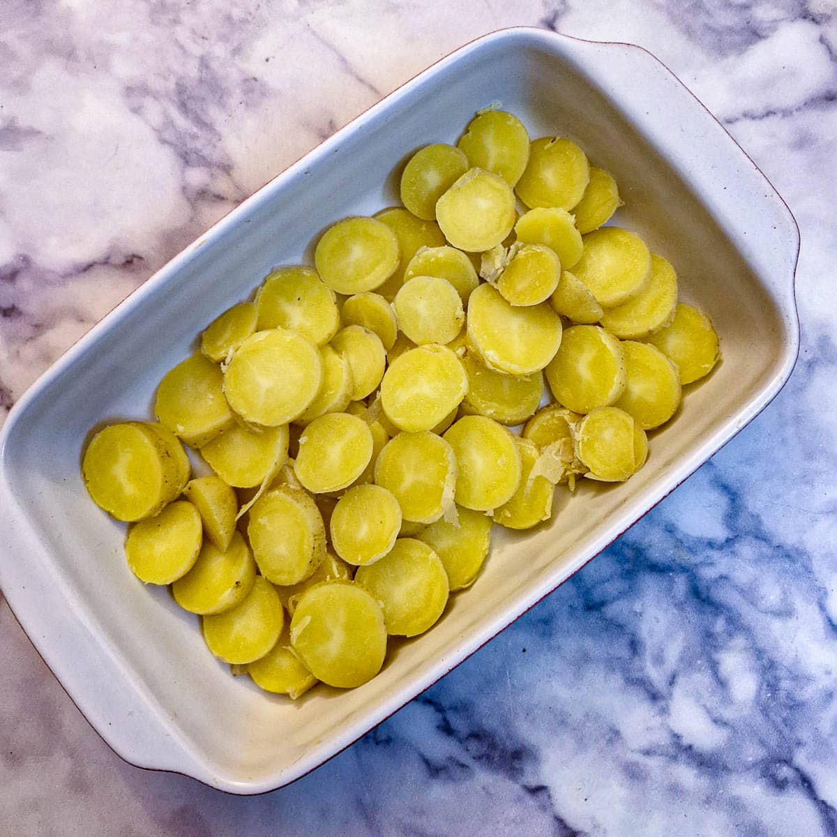 Sliced potatoes in a casserole dish.