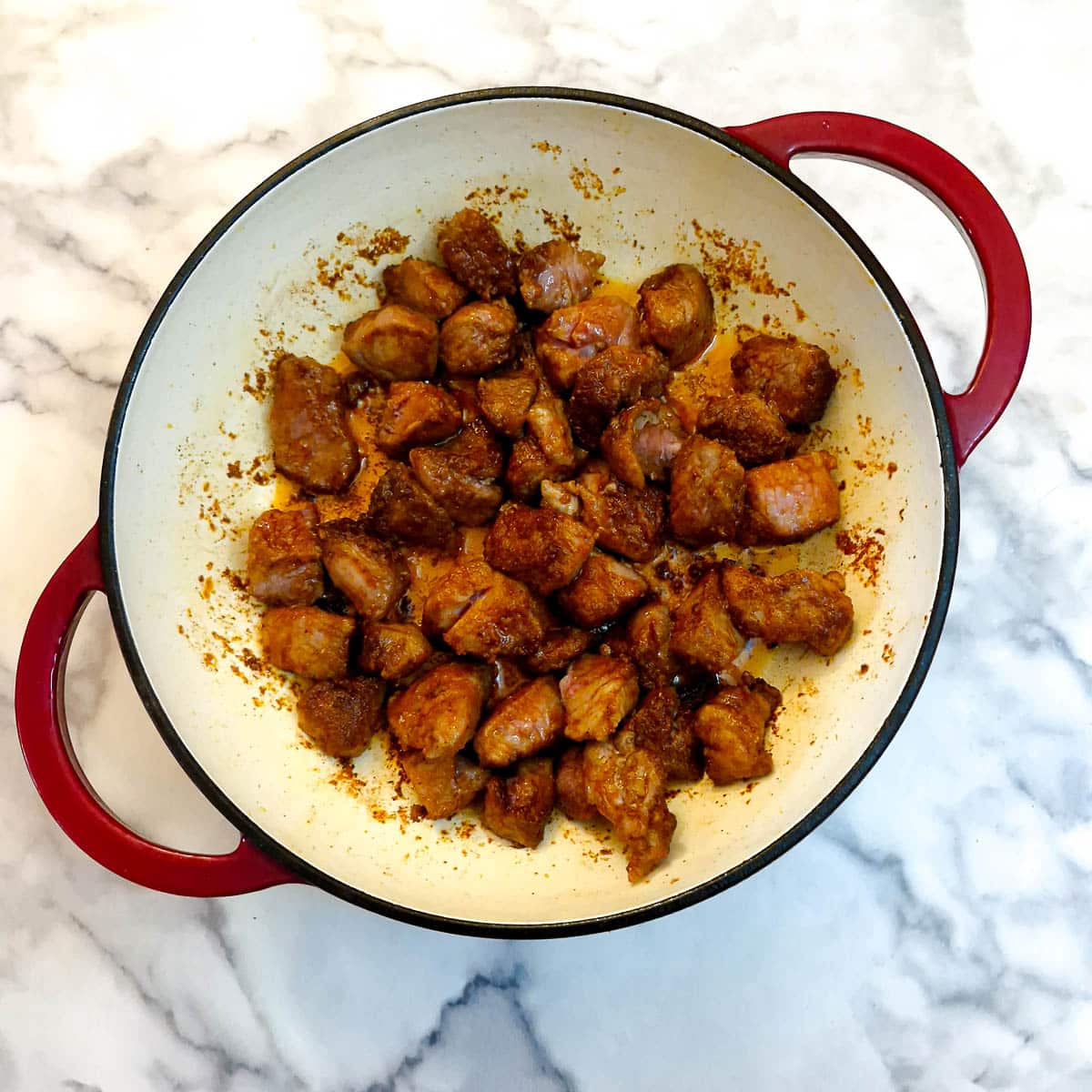 Coated pork frying in a casserole dish.