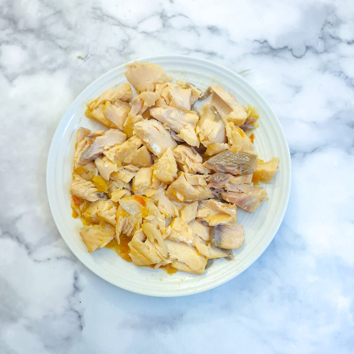 Flaked salmon on a white plate.