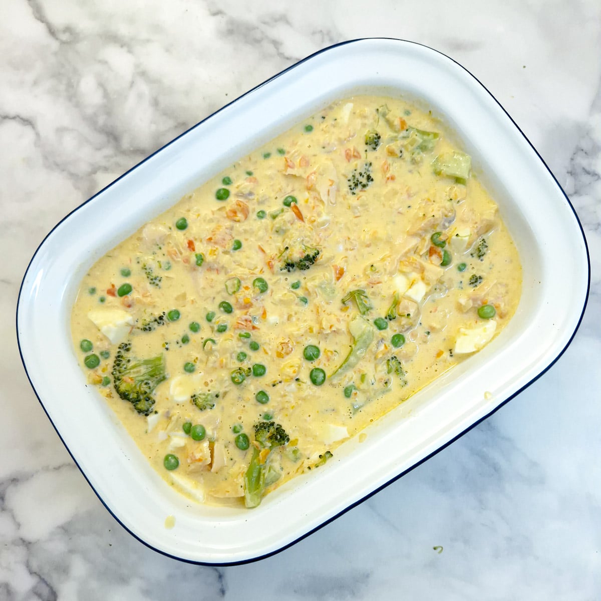 The salmon and red pepper pie filling in a white enamel pie dish.