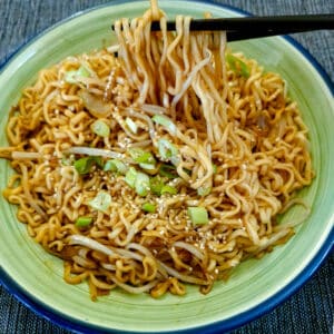 A dish of Chinese stir-fried noodles being lifted with chopsticks.