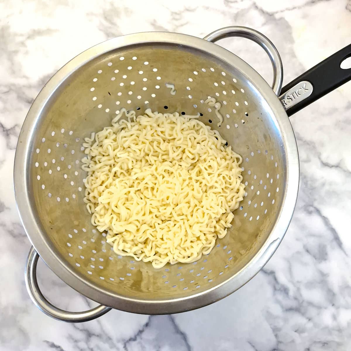 Chinese noodles draining in a colendar.