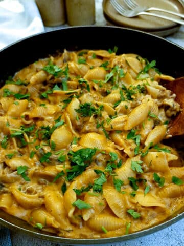 French onion minced beef stroganoff in a frying pan with a large wooden serving spoon.