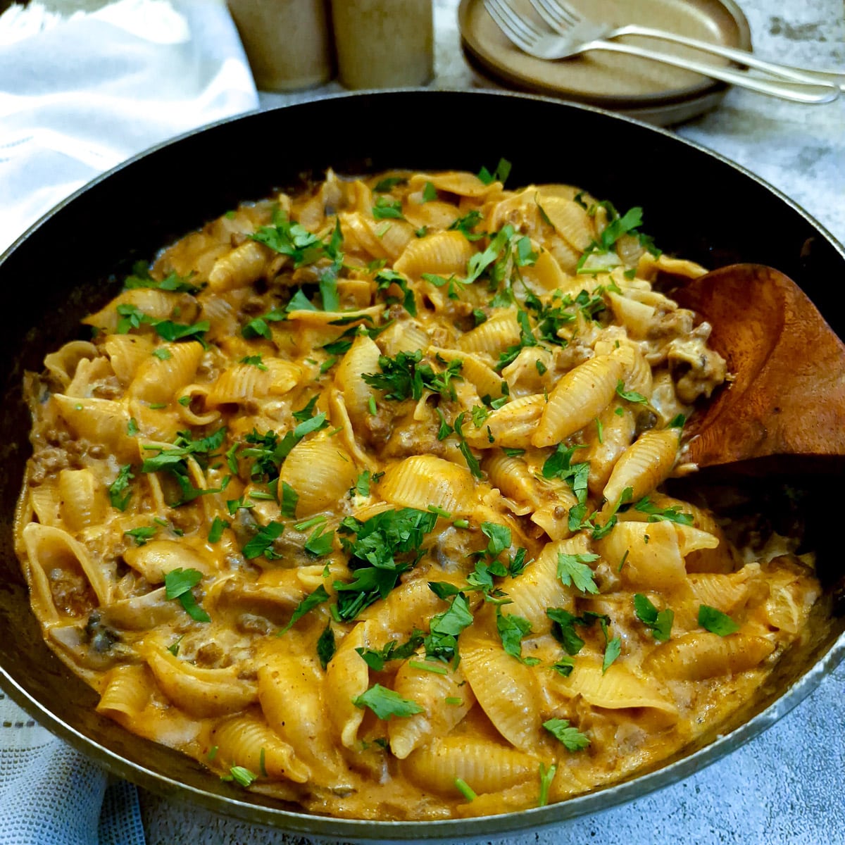 French onion minced beef stroganoff in a frying pan with a large wooden serving spoon.