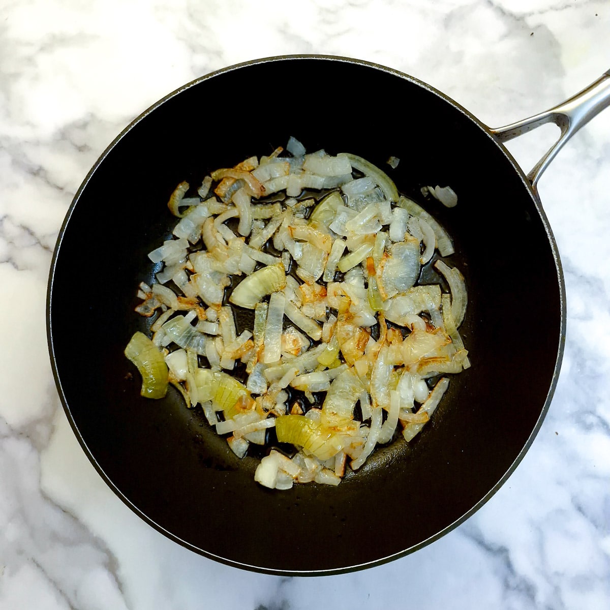Chopped onions softening in a frying pan.