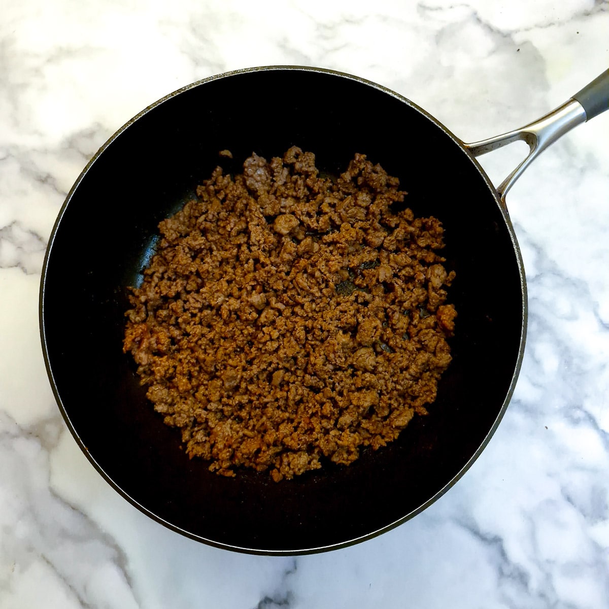 Ground beef fried until crumbly in a frying pan.