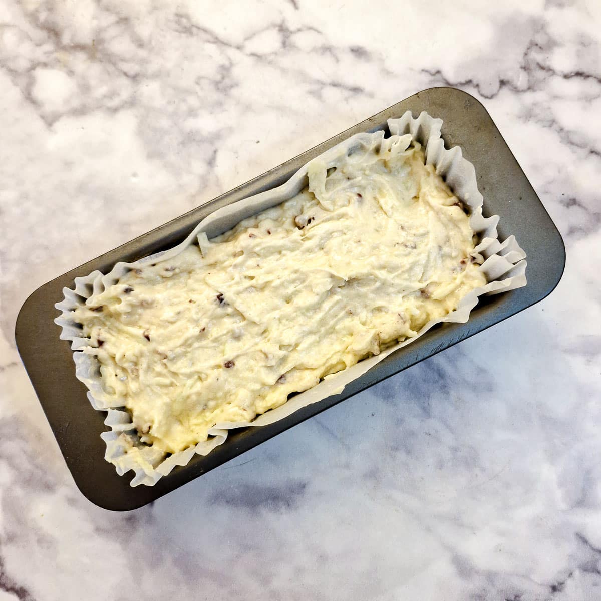 Raw cake batter in a cake tin ready for the oven.