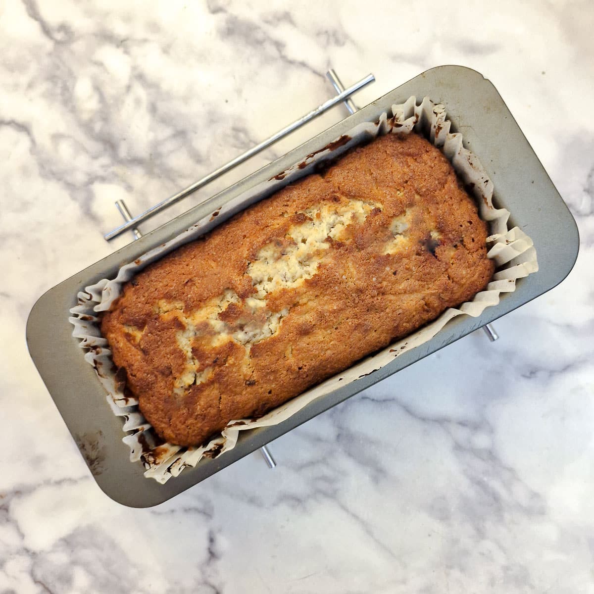 A nicely browned apple and pecan nut loaf in an oblong baking tin.