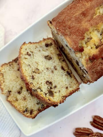 Overhead shot of an apple and pecan loaf with 2 slices lying flat on the plate.