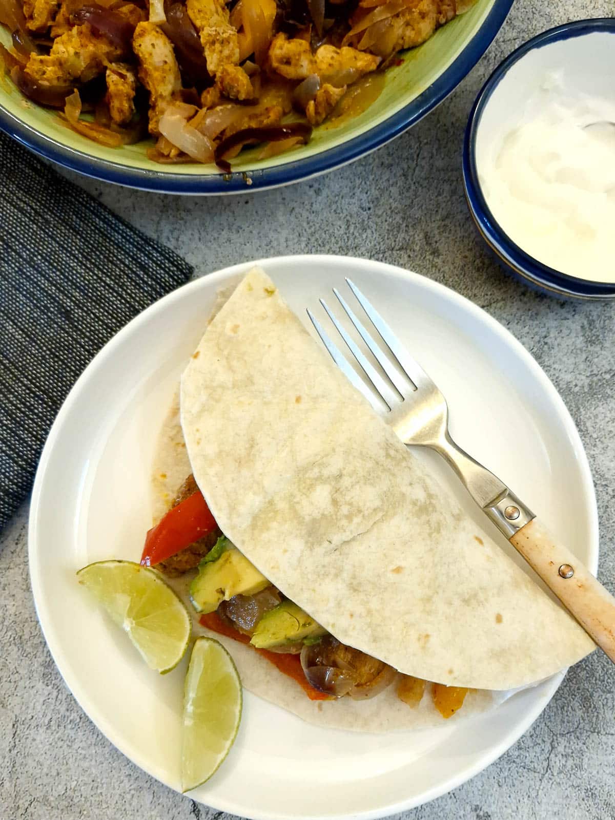 Chicken fajita wrapped in a flour tortilla on a white plate.