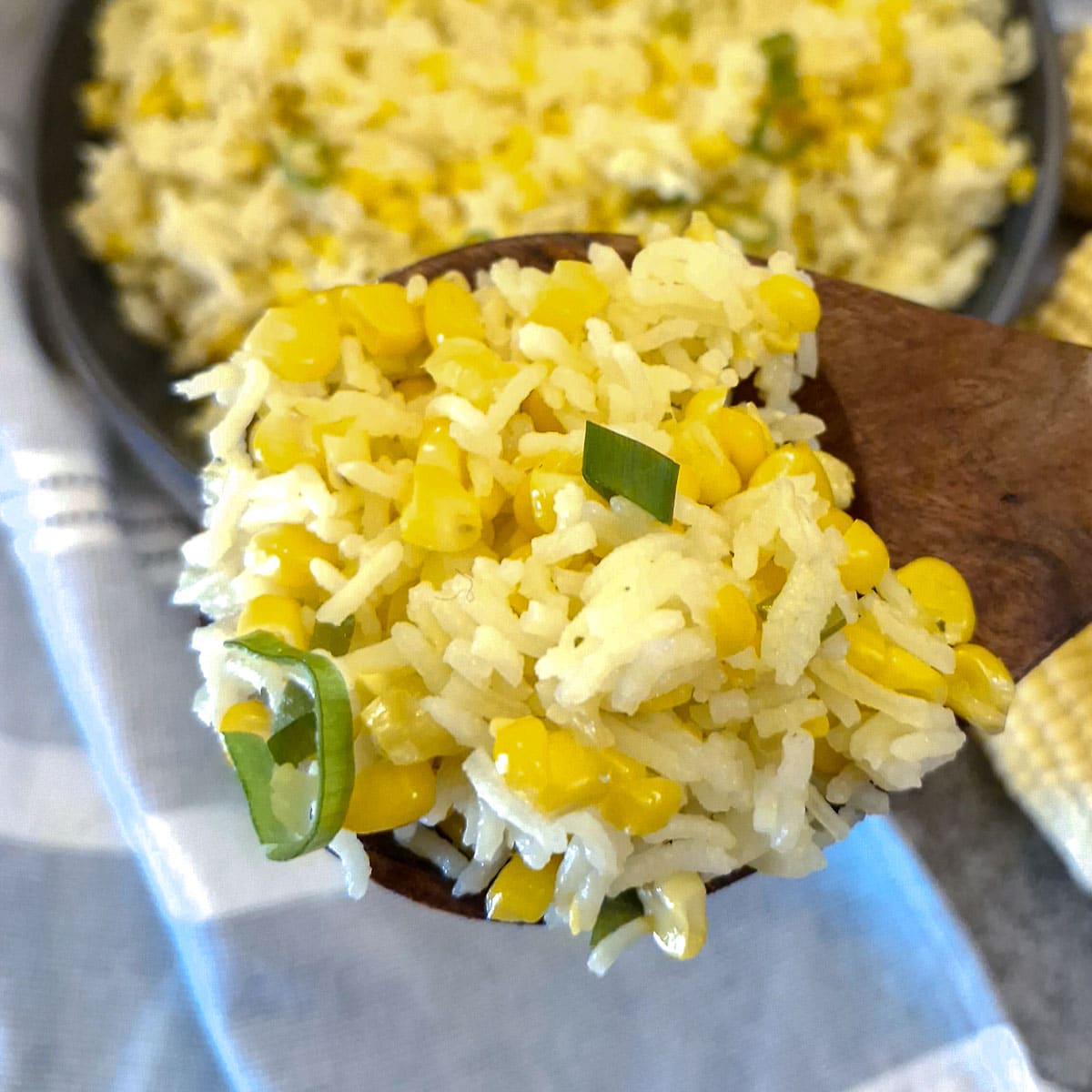 A spoonful of buttered corn and rice held over the serving dish.