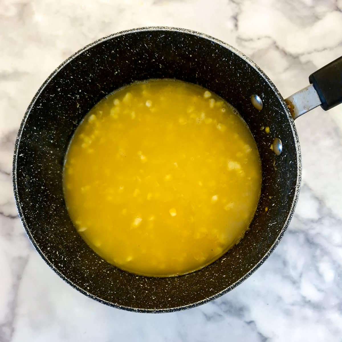 Chicken stock added to the saucepan.,