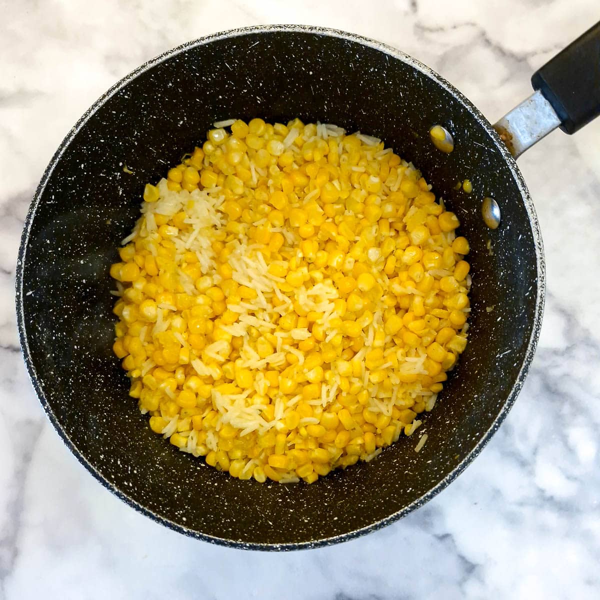 Corn and rice in a saucepan after having simmered for 12 minutes.